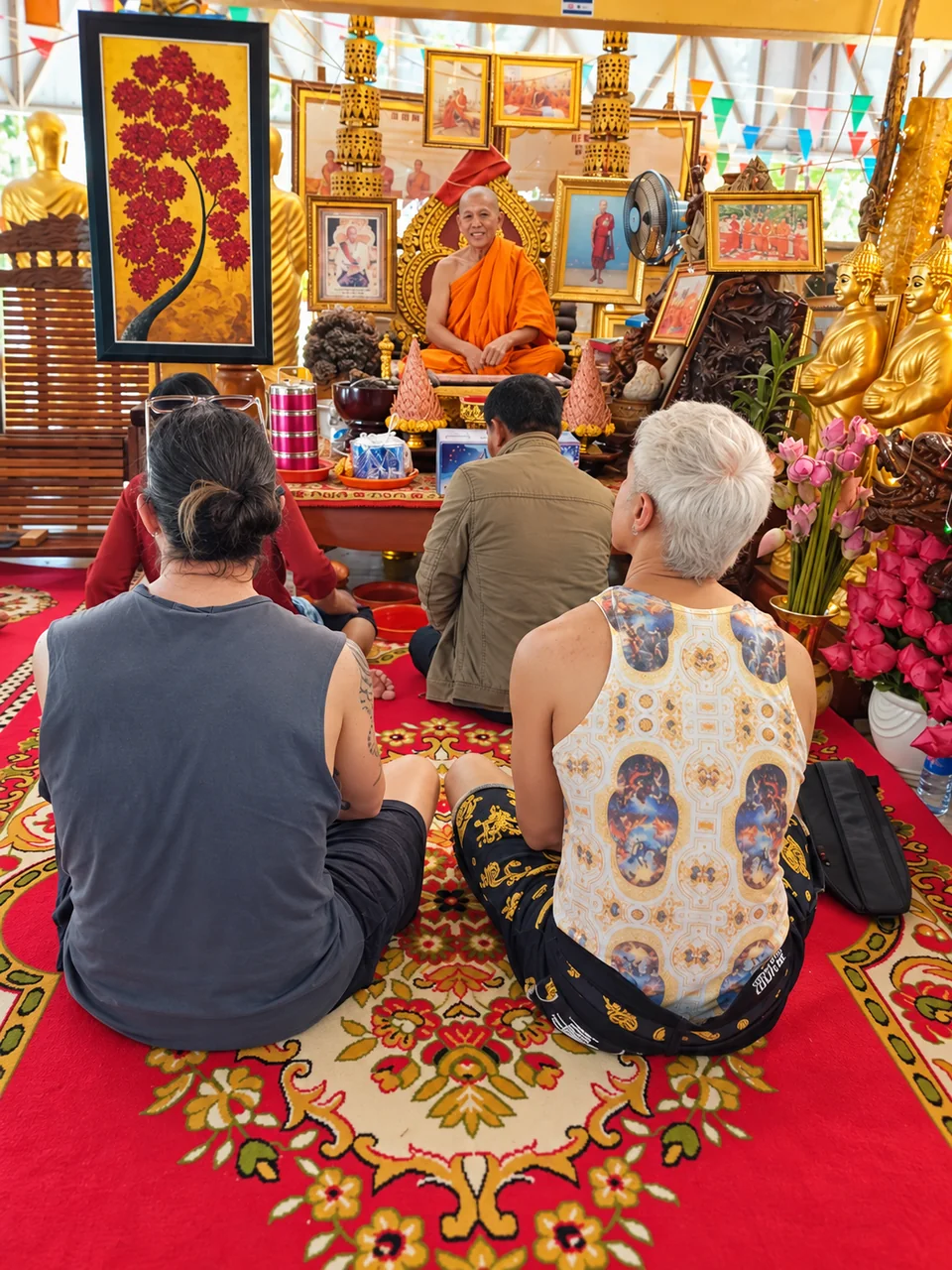 Travelers seated in prayer before a Buddhist monk